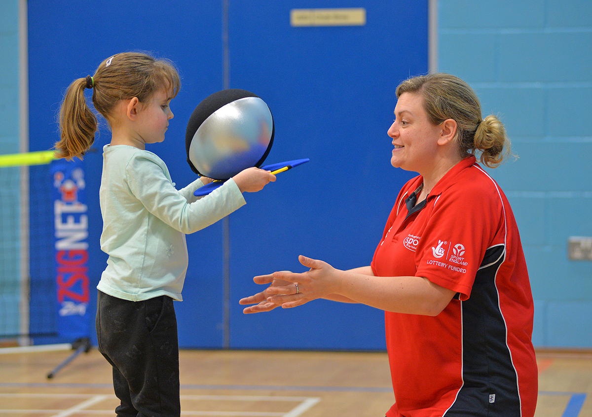 Young visually impaired girl playing adapted tennis game