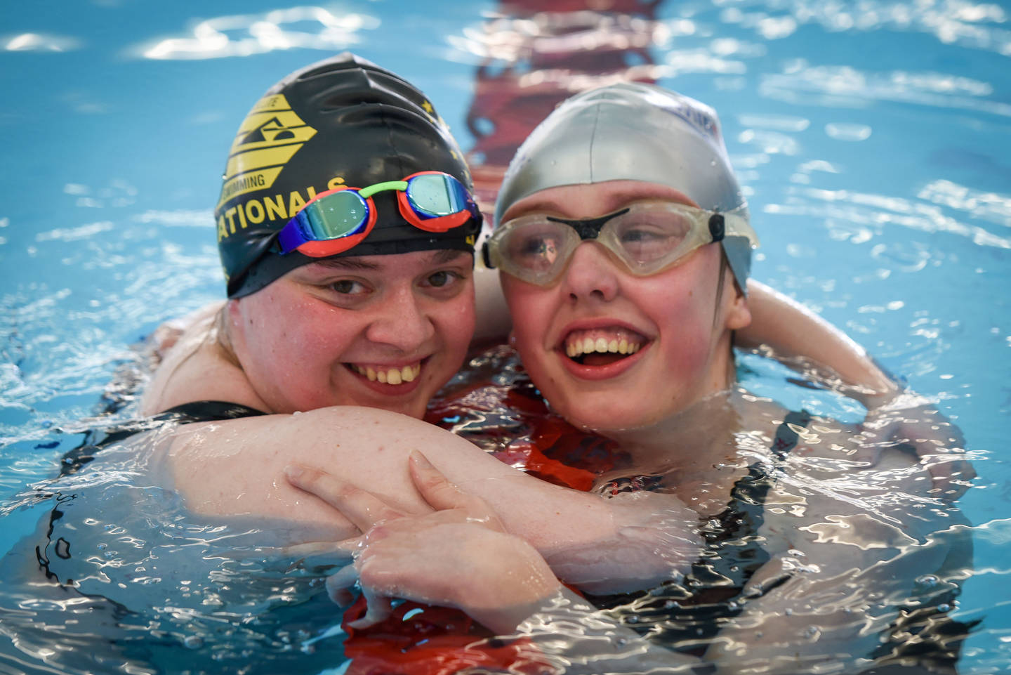 Two swimmers hugging at the end of a race in pool