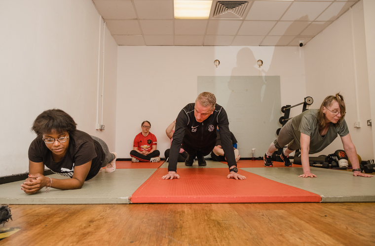 Three people do a plank in a gym class.