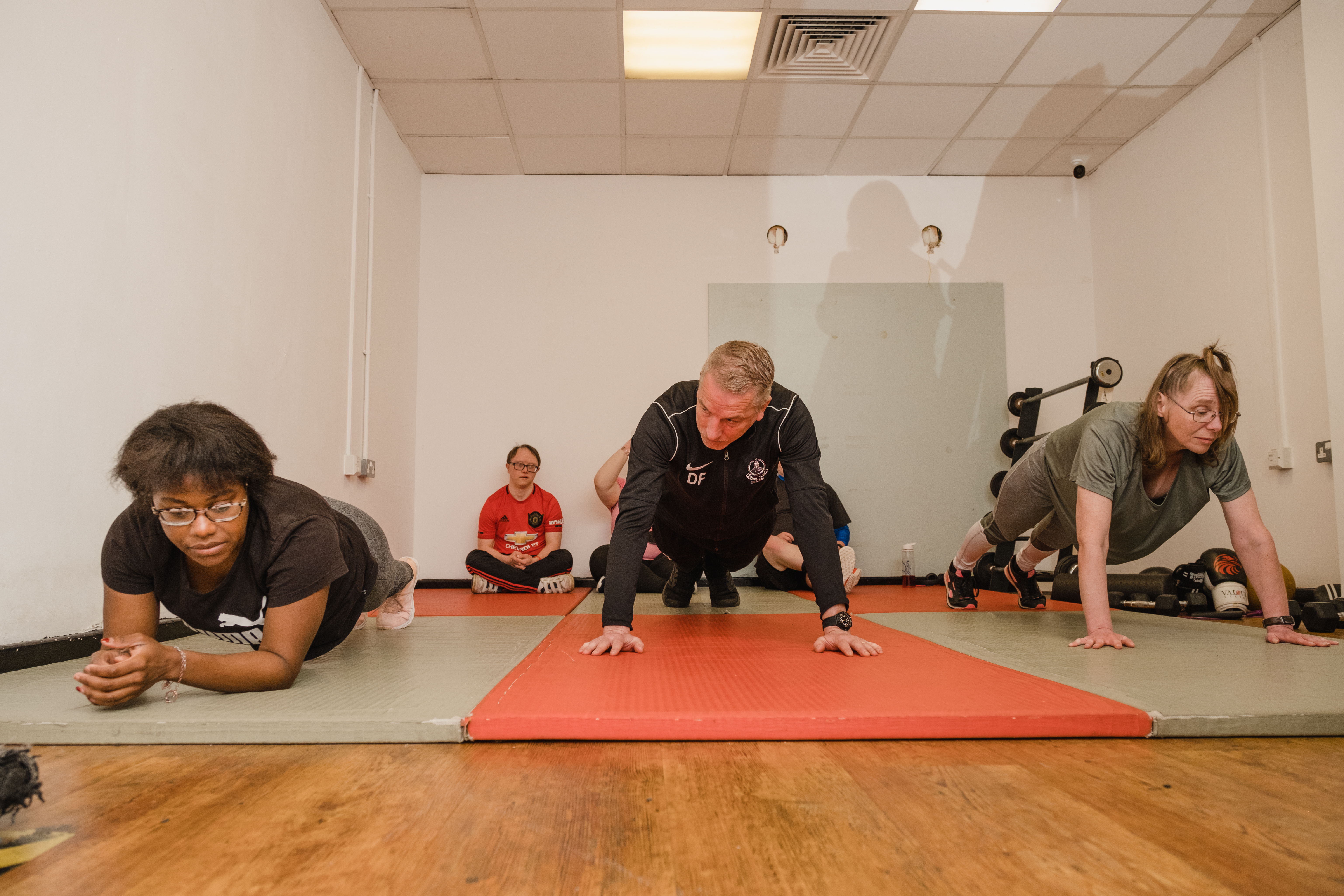 Three people do a plank in a gym class.