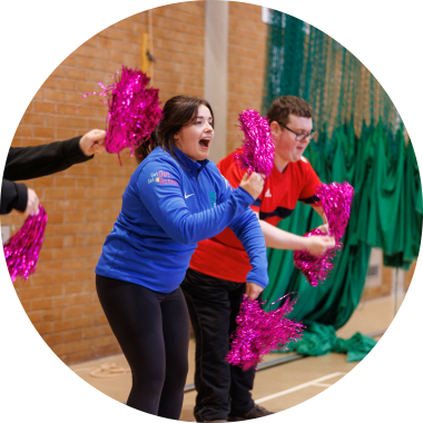 Group of disabled and non-disabled people taking part in a dance session using pom poms. 