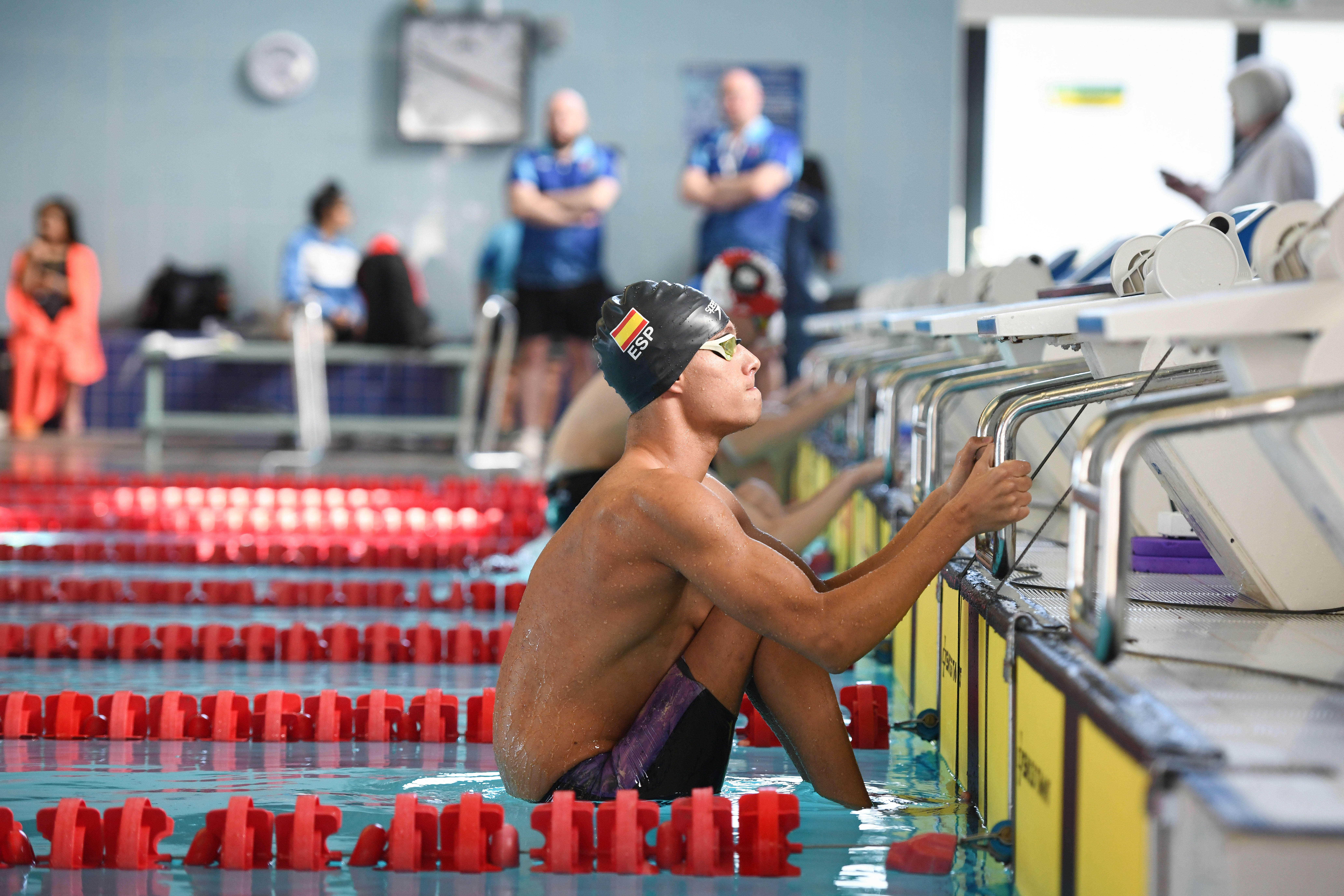 A man in a Spanish swimming cap ready to start a backstroke race in the pool.