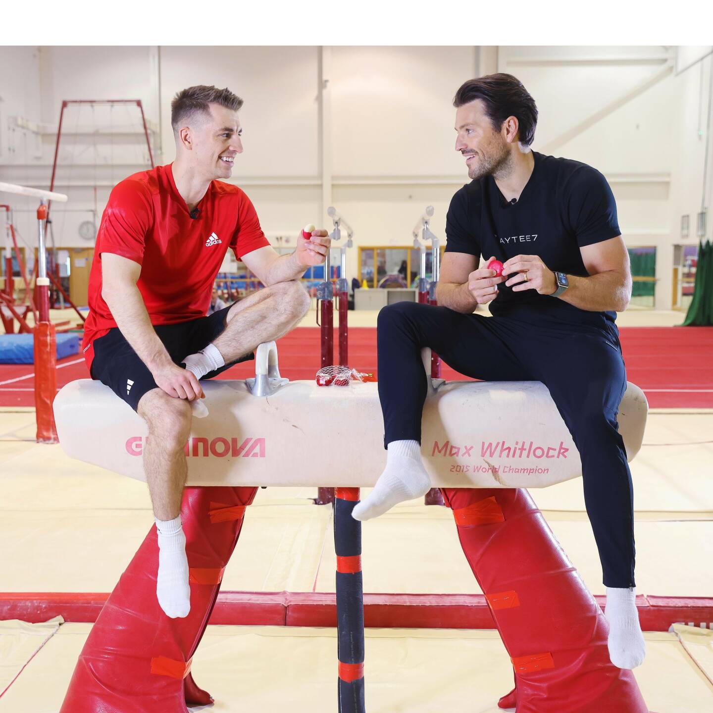 Max Whitlock and Mark Wright sit on a pummel horse and have a chat while eating Babybel cheese.
