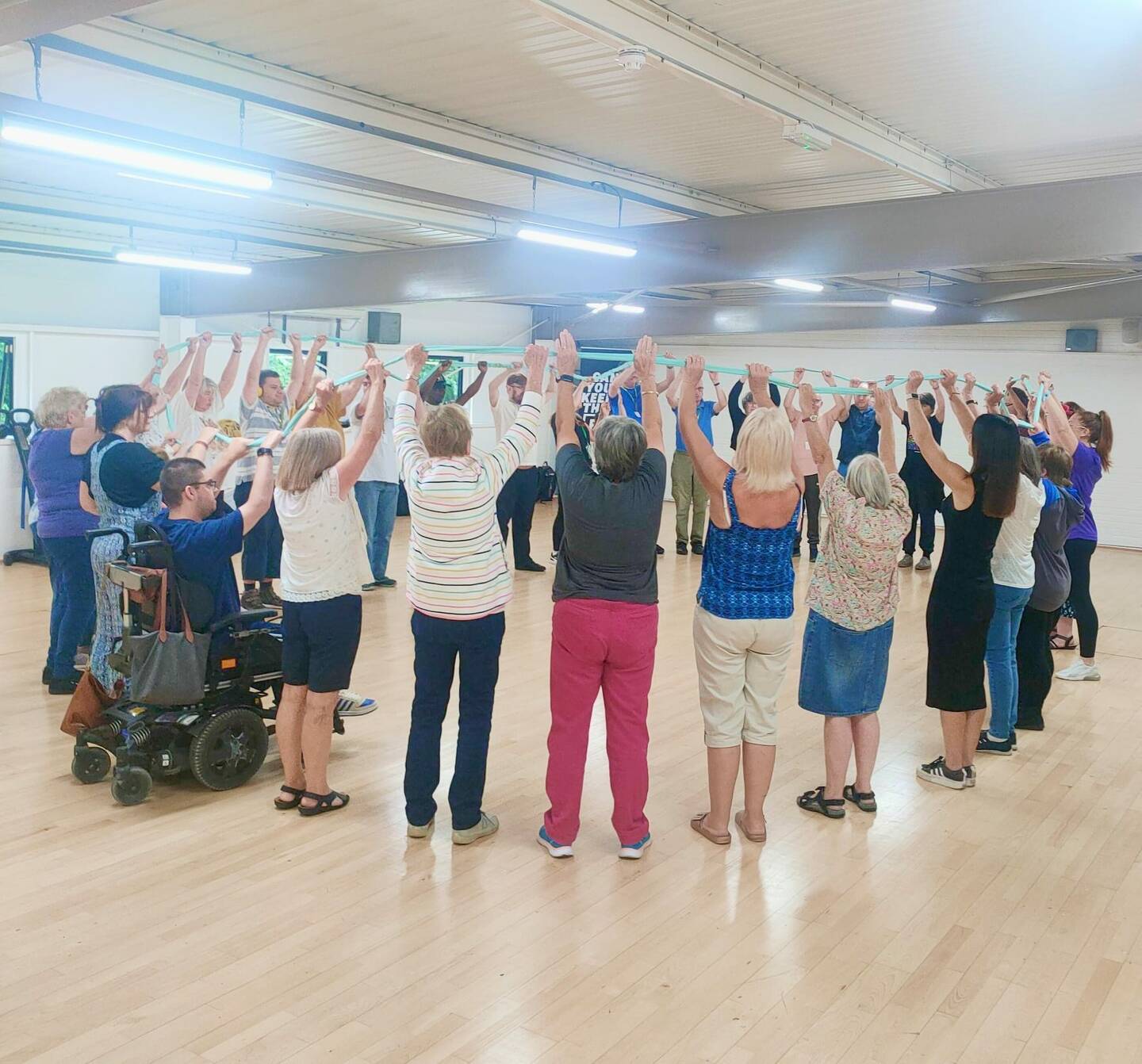 A group of people in a gym stand in a circle.