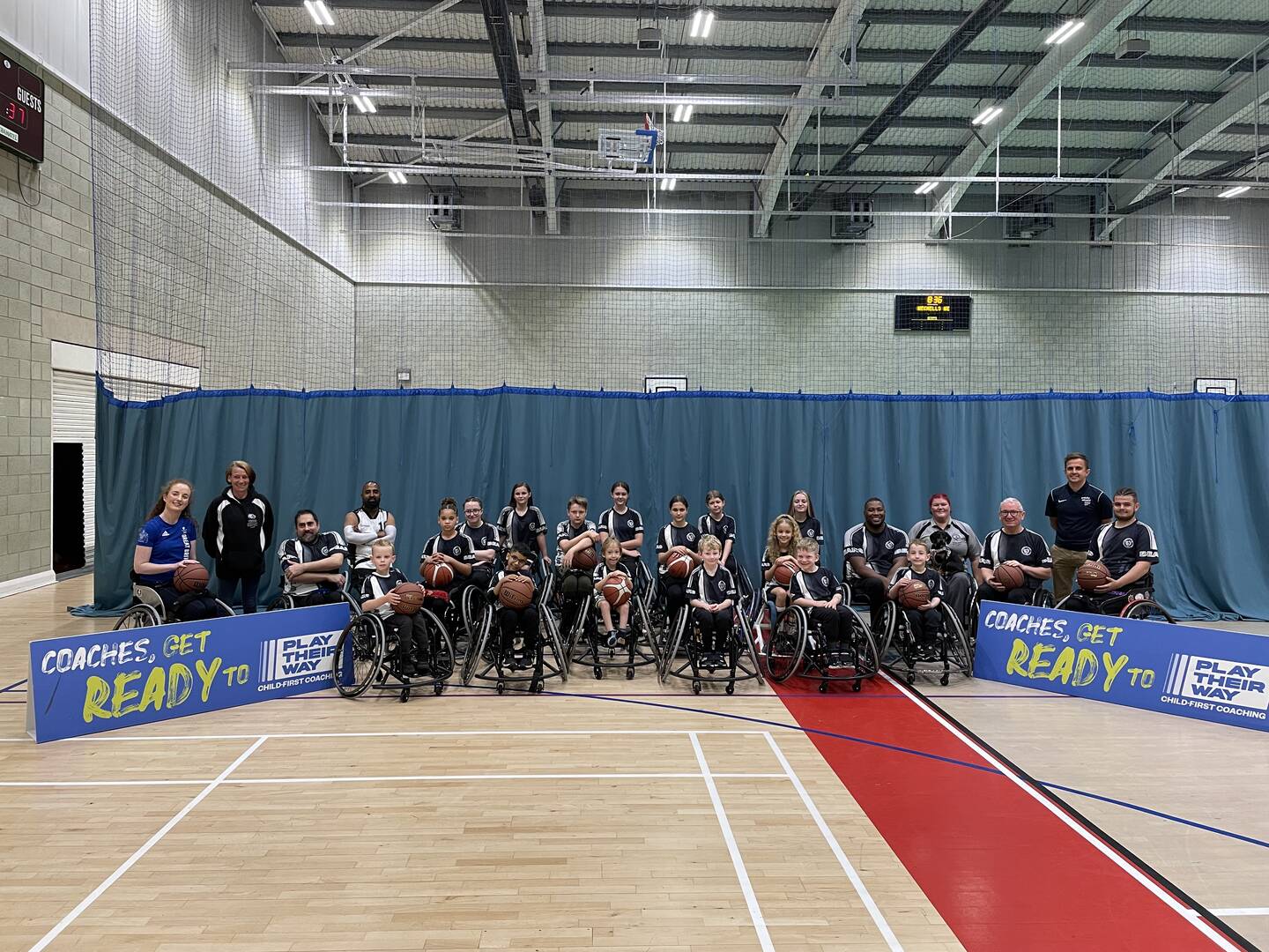 A wheelchair basketball team pose alongside Play Their Way banners.