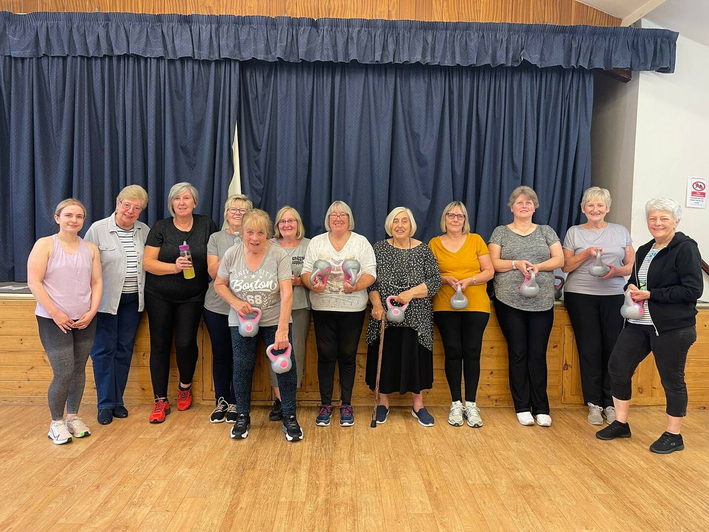 A group of people stand in a village hall.