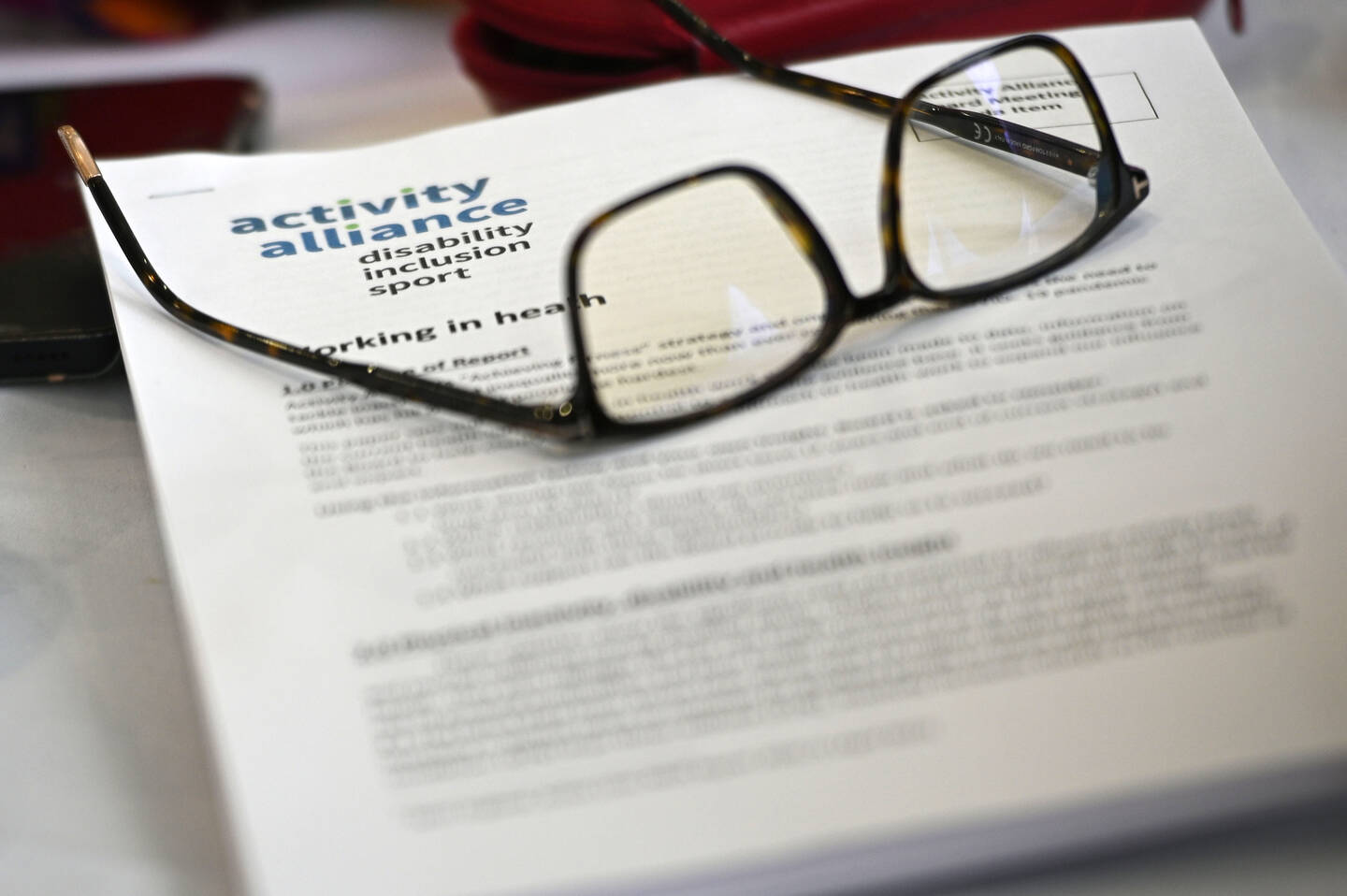 A pair of glasses on top of a piece of paper with the Activity Alliance logo on.