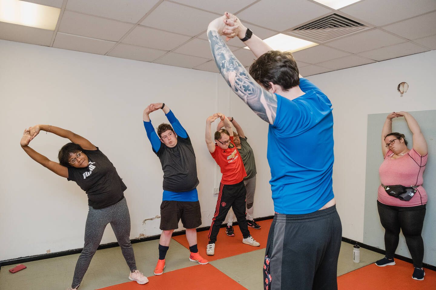 Group of people taking part in an exercise class. They are standing in a group and stretching.