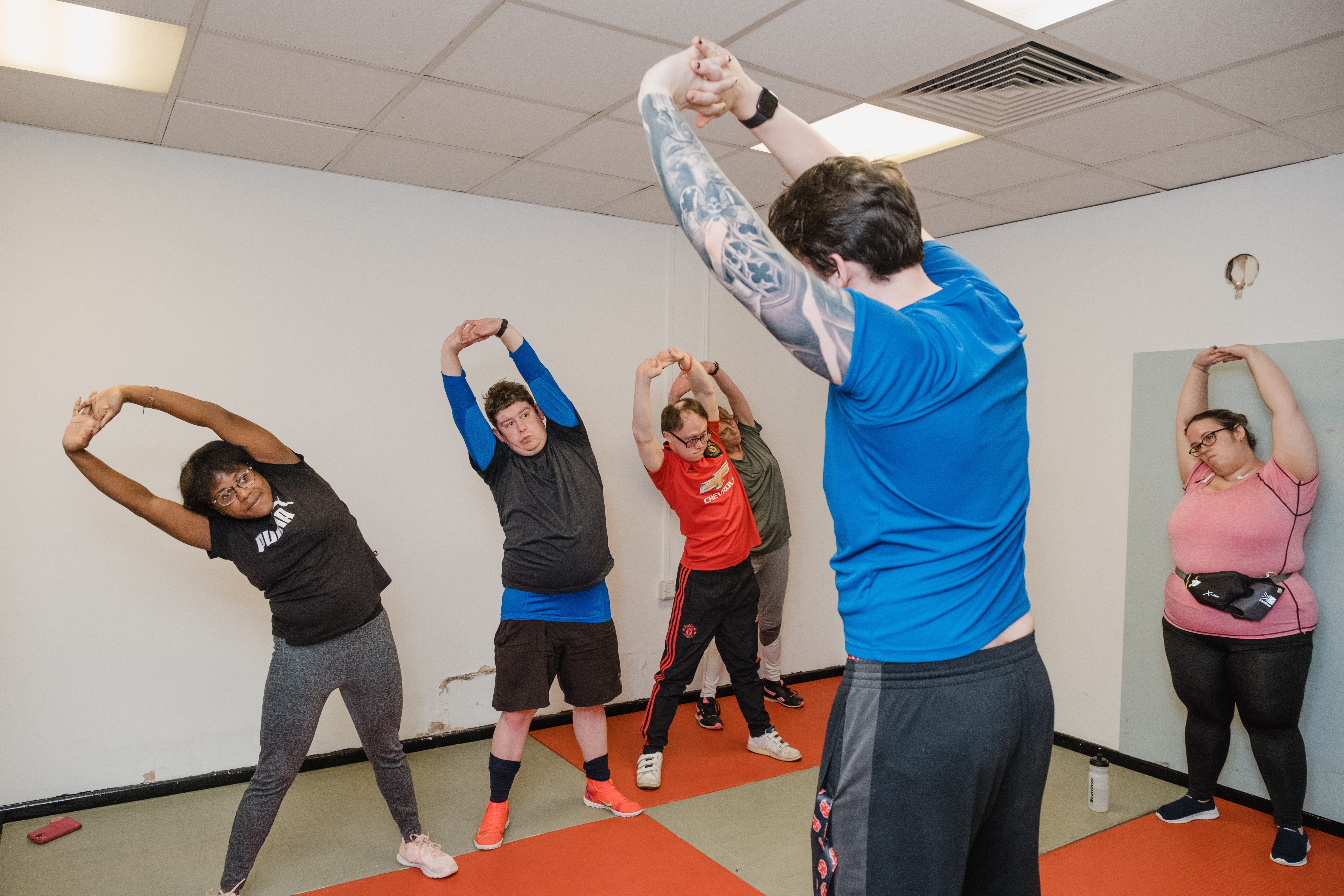 Group of people taking part in an exercise class. They are standing in a group and stretching.